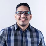 Casual portrait of a smiling man wearing glasses and a plaid shirt.
