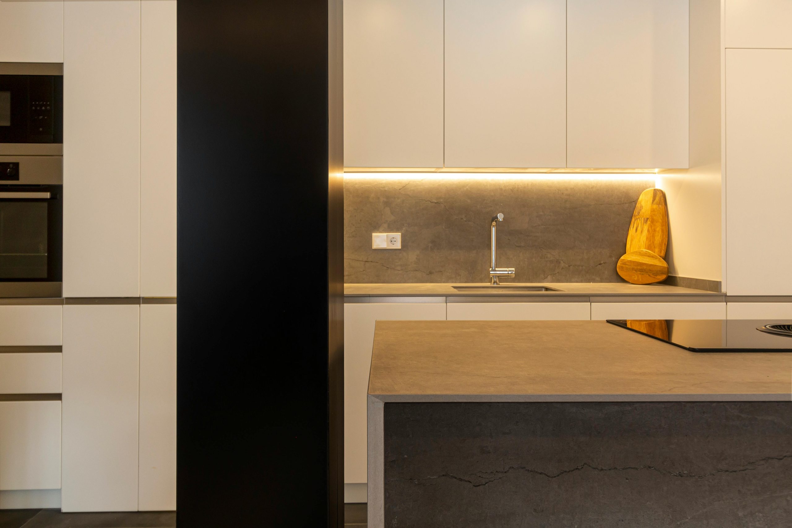 A stylish kitchen featuring modern design with minimalist elements and warm lighting.